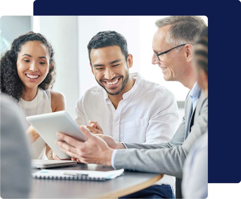 Group of diverse employees sitting at a conference table reviewing something on a tablet